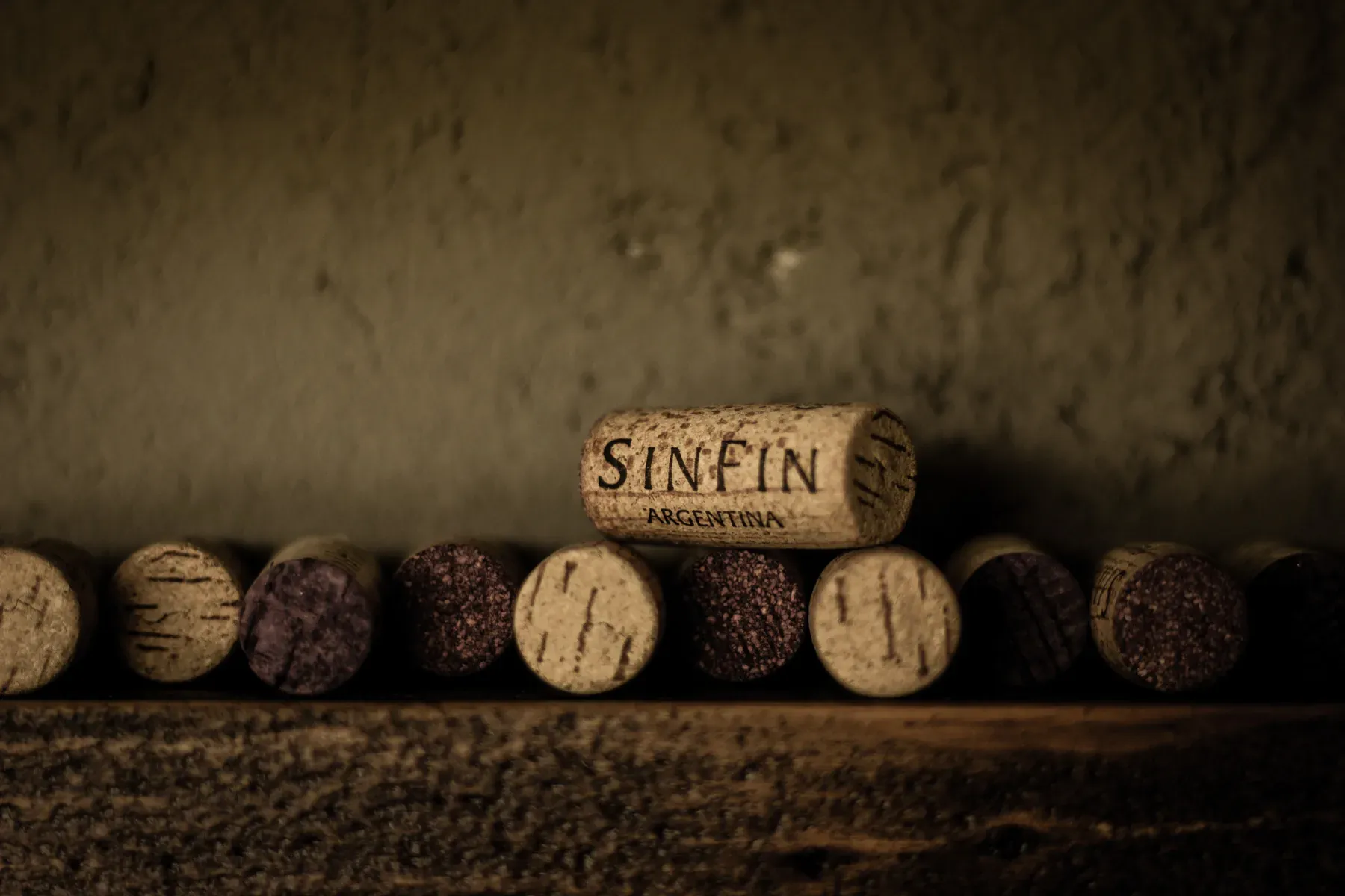 Corchos de Bodega SinFin alineados sobre una repisa de madera en la cava